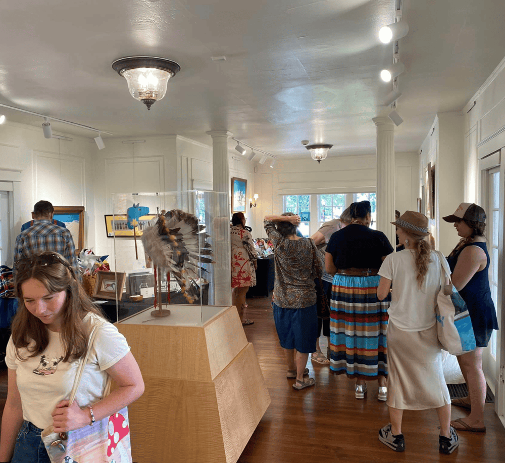 Colorful art gallery exhibit with visitors exploring and appreciating Native American jewelry and artwork.