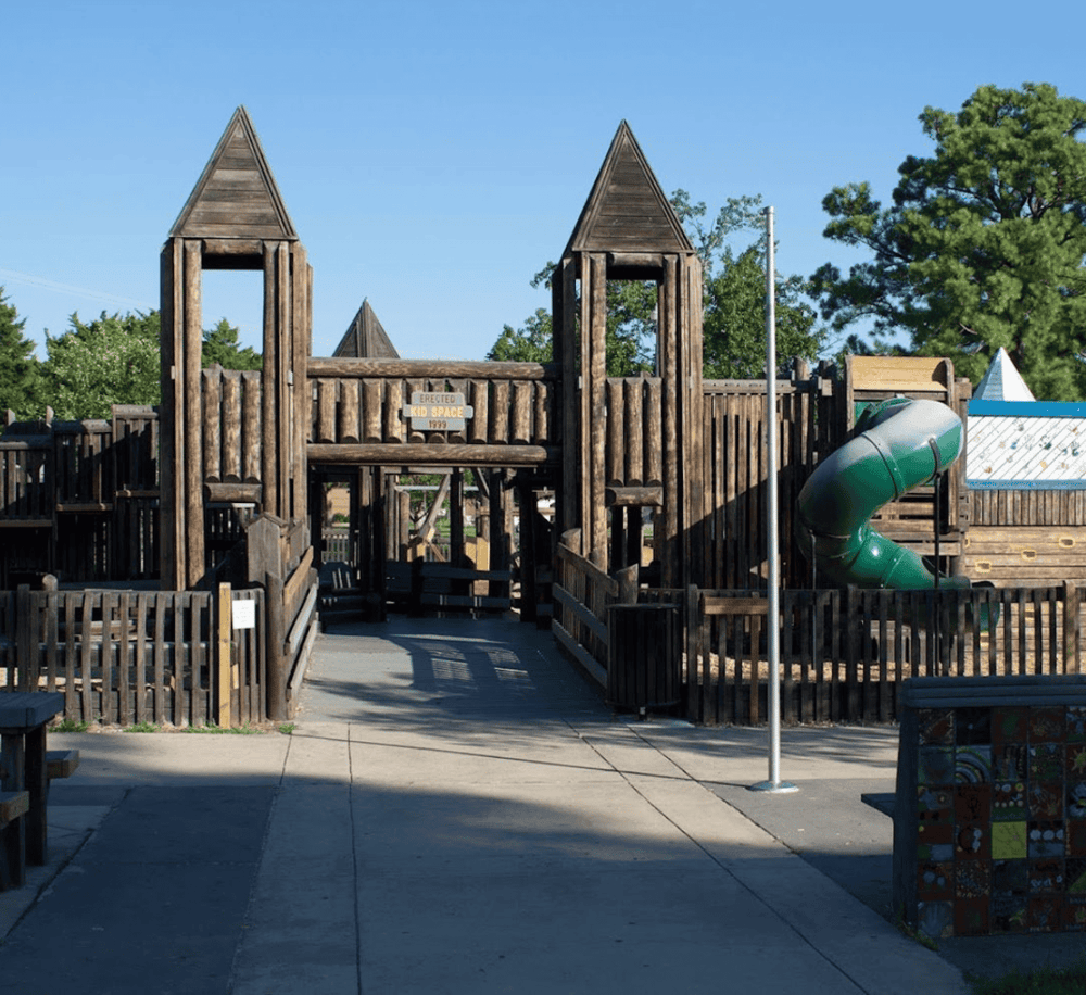 Wooden playground castle with slides and kid-friendly structures at Quest For Directions.