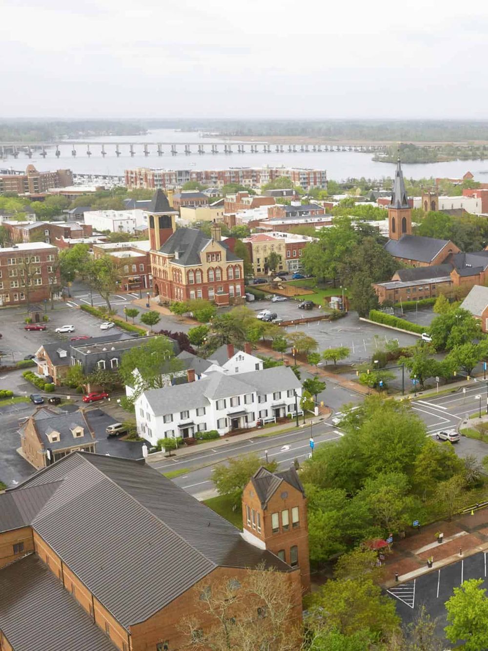 Aerial view of a charming town with historic buildings, church, and scenic river, showcasing QuestForDirections' local expertise.