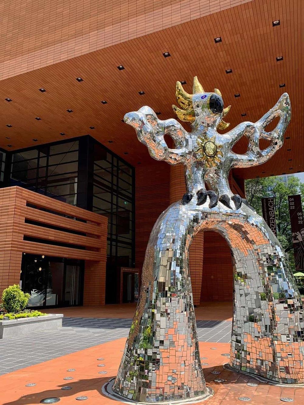 Vibrant mosaic sculpture outside Quest for Directions building, art installation, modern architectural design, city landmark.