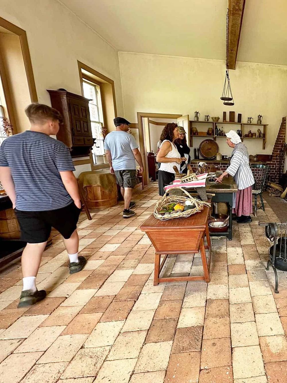 Traditional farmhouse kitchen with visitors experiencing historical cooking demonstrations.