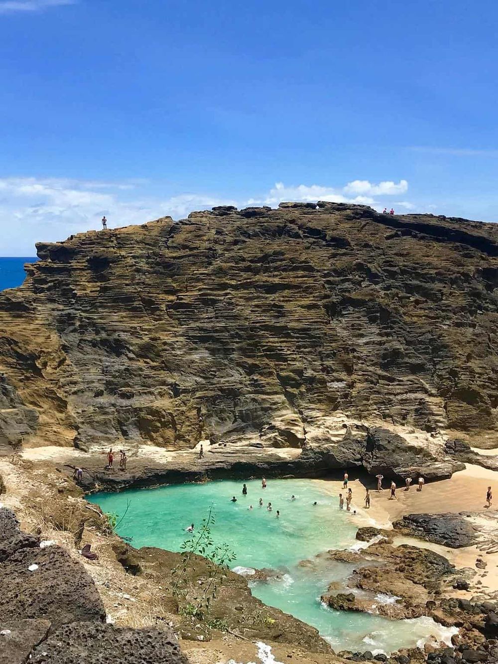 Secluded beach with turquoise water and rugged cliffs, popular for swimming and sightseeing.