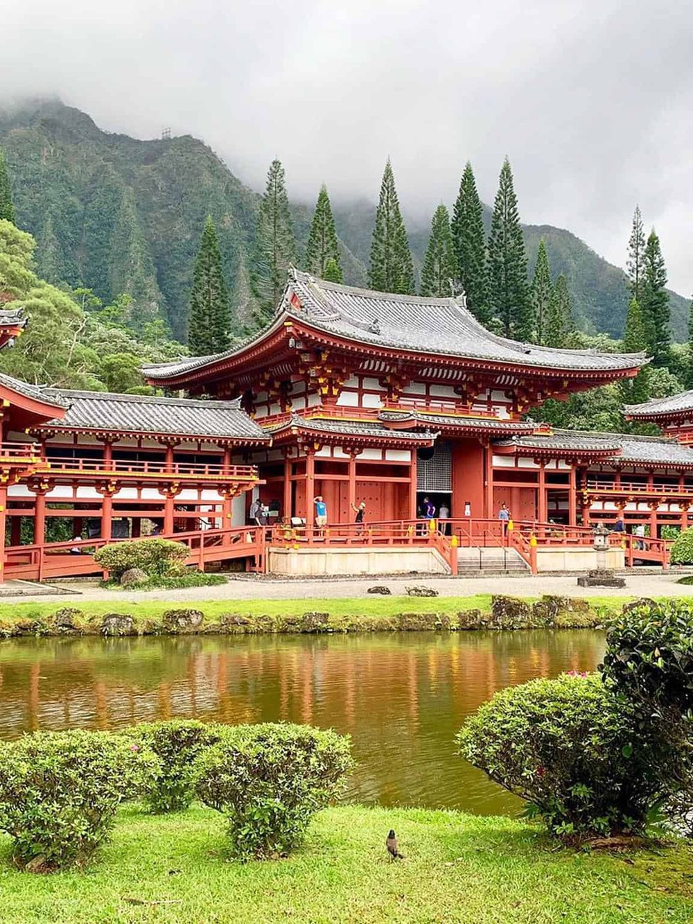 Traditional Japanese temple in lush garden with pond and mountain backdrop, popular for cultural exploration and serene sightseeing.