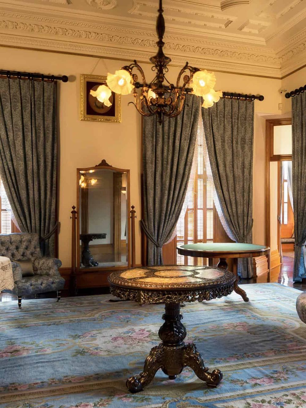 Elegant vintage living room with ornate chandelier, antique furniture, and lush drapes, showcasing classic interior decor.