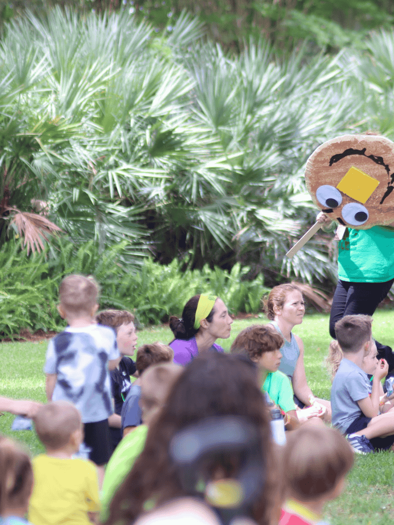 A fun outdoor educational activity for children with a person dressed as a worm character.