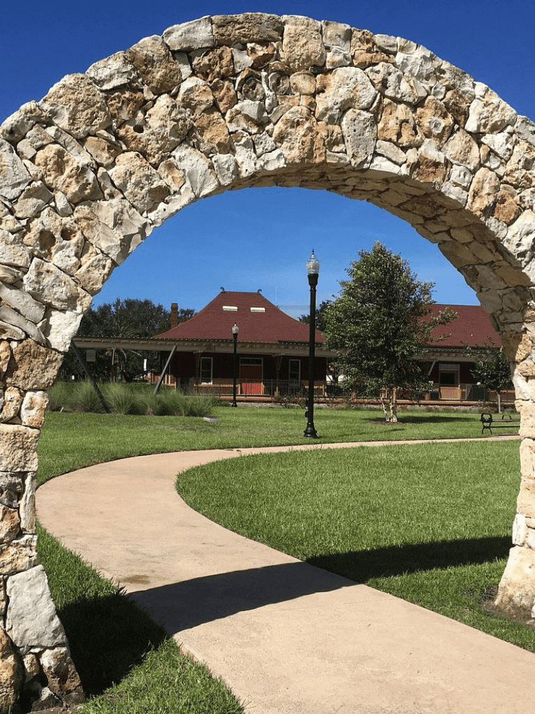 Stone archway at QuestForDirections, scenic park with walking path and historic building, outdoor location, downtown, Texas.