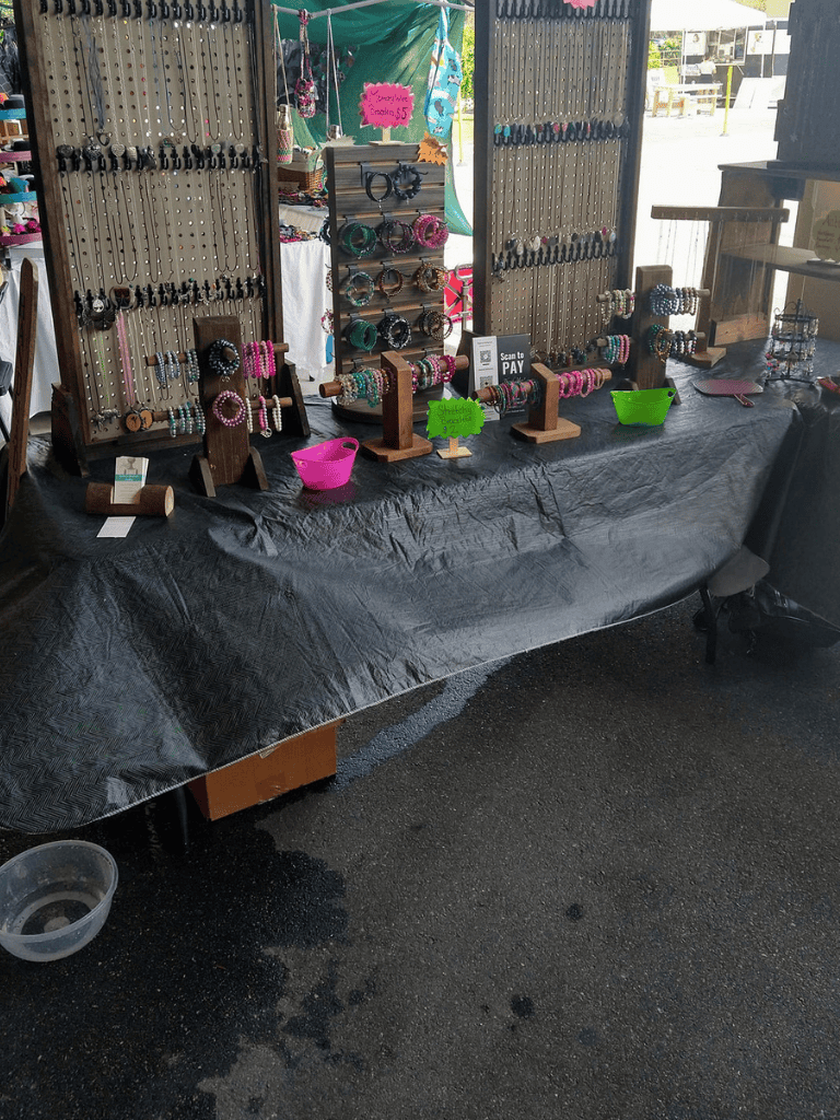 Colorful beaded jewelry display at local craft market, handmade bracelets and accessories for sale.