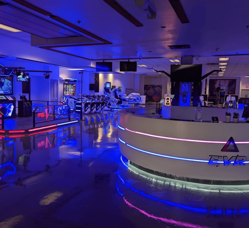 Bright indoor arcade with neon lights, gaming stations, and VR attractions.