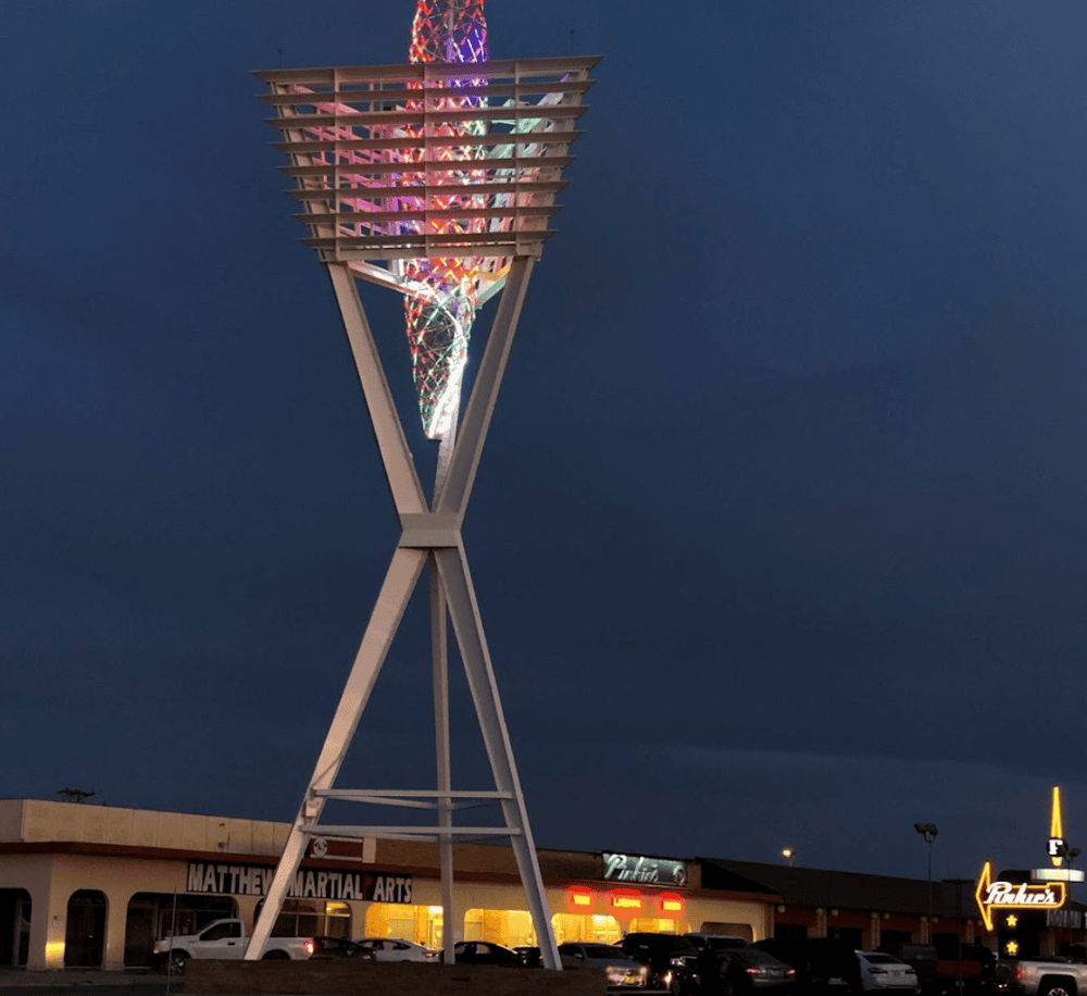 Brightly lit observation tower with colorful LED lights at night in Quest for Directions location.