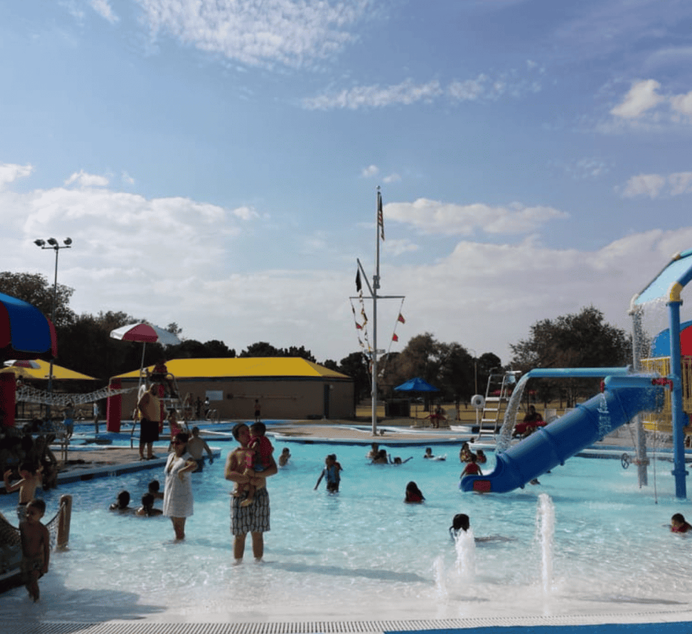 Vast family-friendly outdoor water park with slides, splash zones, and vibrant umbrellas for a fun summer day.