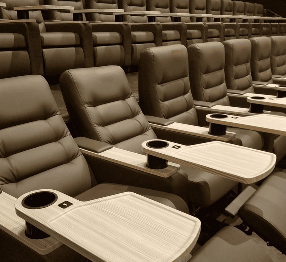 Comfortable theater seats with built-in tables for a premium entertainment experience.