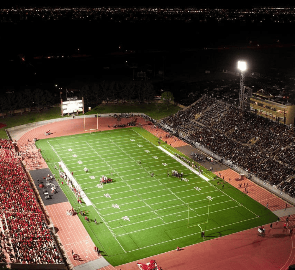 Brightly lit football stadium at night with packed stands and field ready for game day.