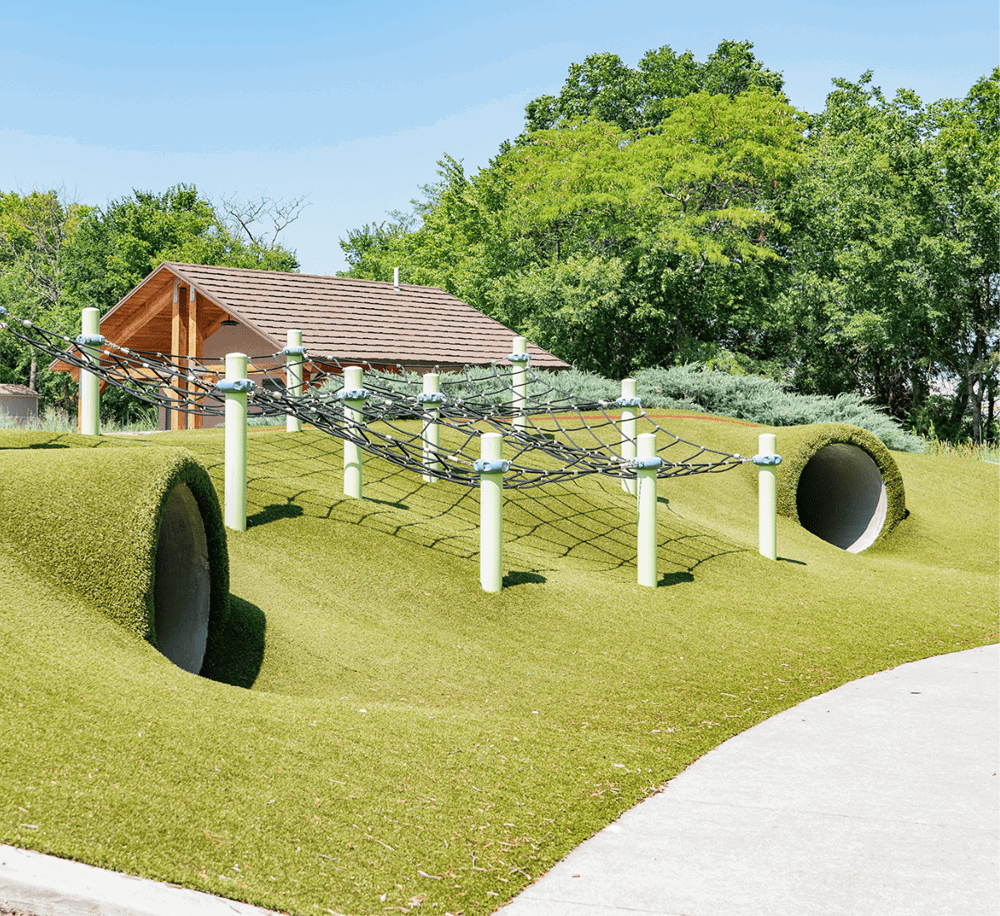 Colorful playground equipment with tunnels and climbing ropes in a park setting.