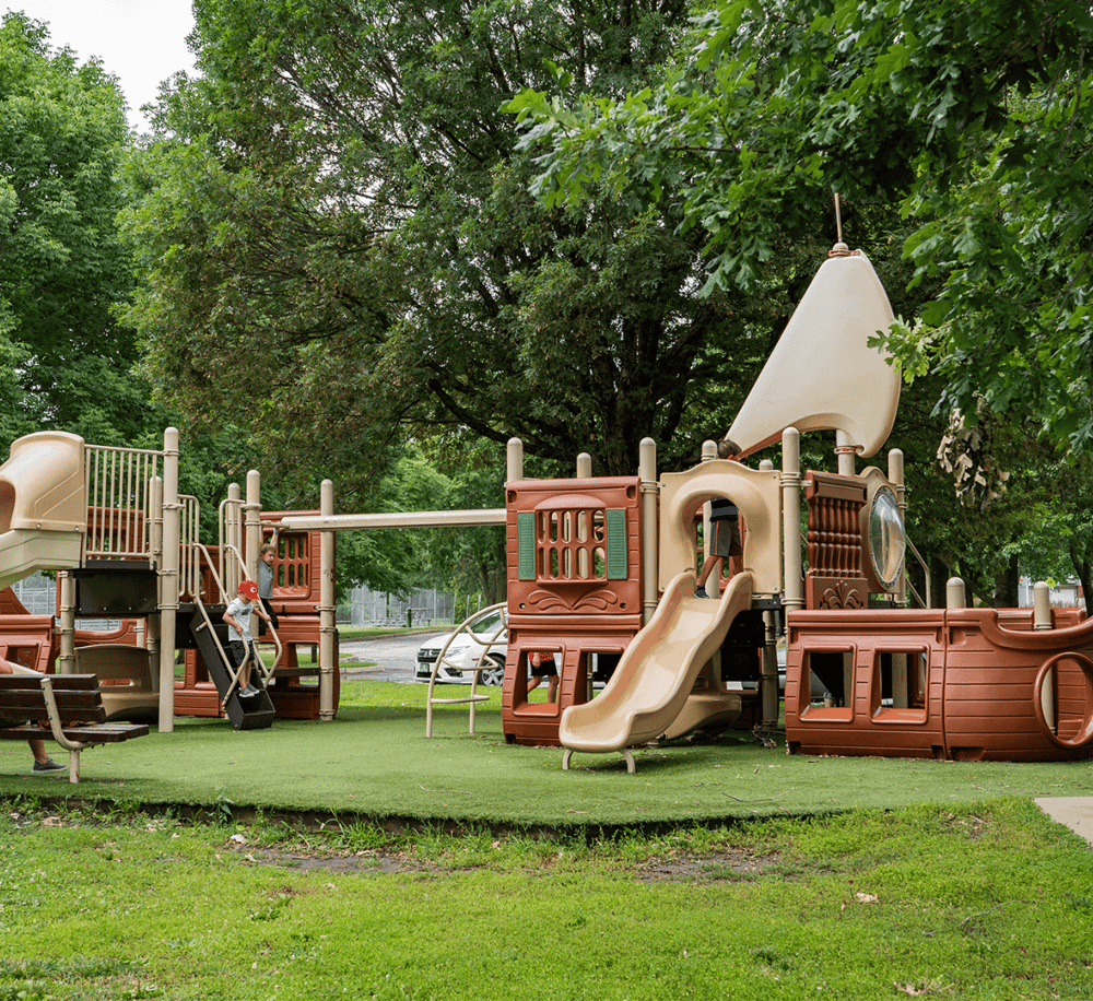Colorful children's playground designed for fun and adventure with slides, climbing structures, and all-weather turf surface.