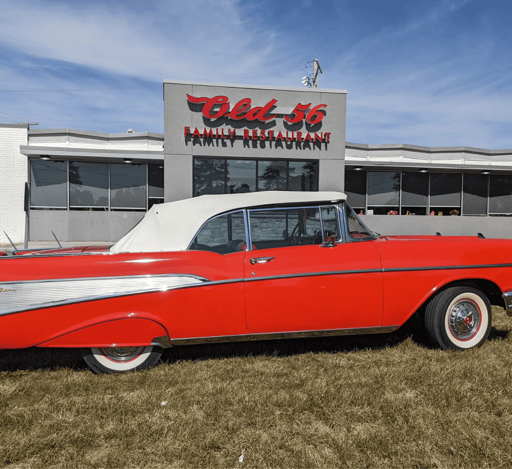 Vintage red and white classic car parked outside Old 56 Family Restaurant.