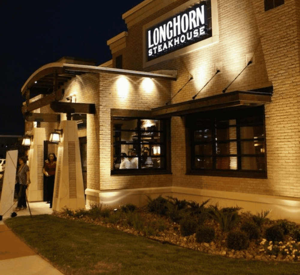 Elegant exterior of LongHorn Steakhouse at night, illuminated by warm lighting.