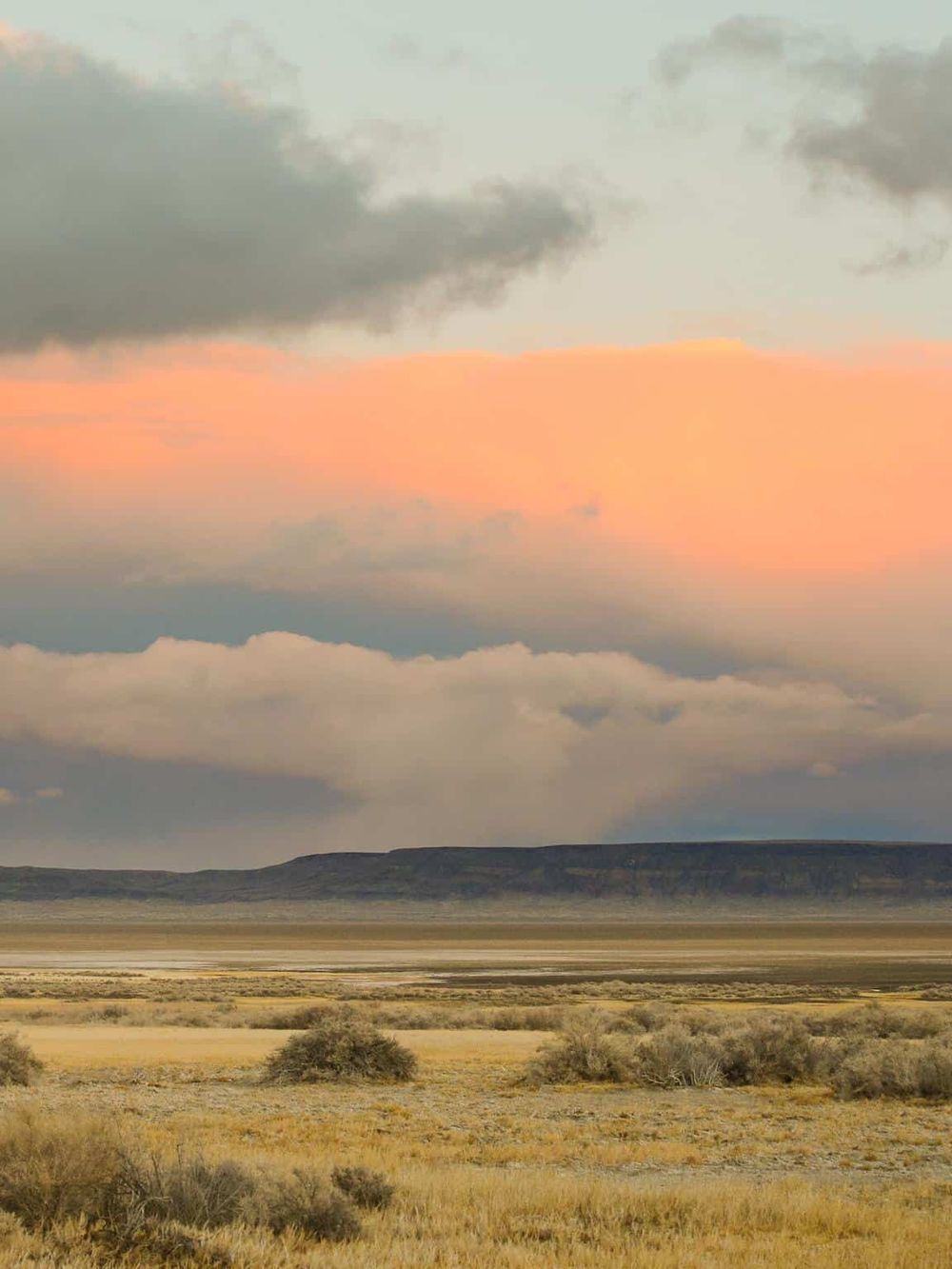 Vast desert landscape with colorful sky and distant mountains, inspiring adventure and navigation.