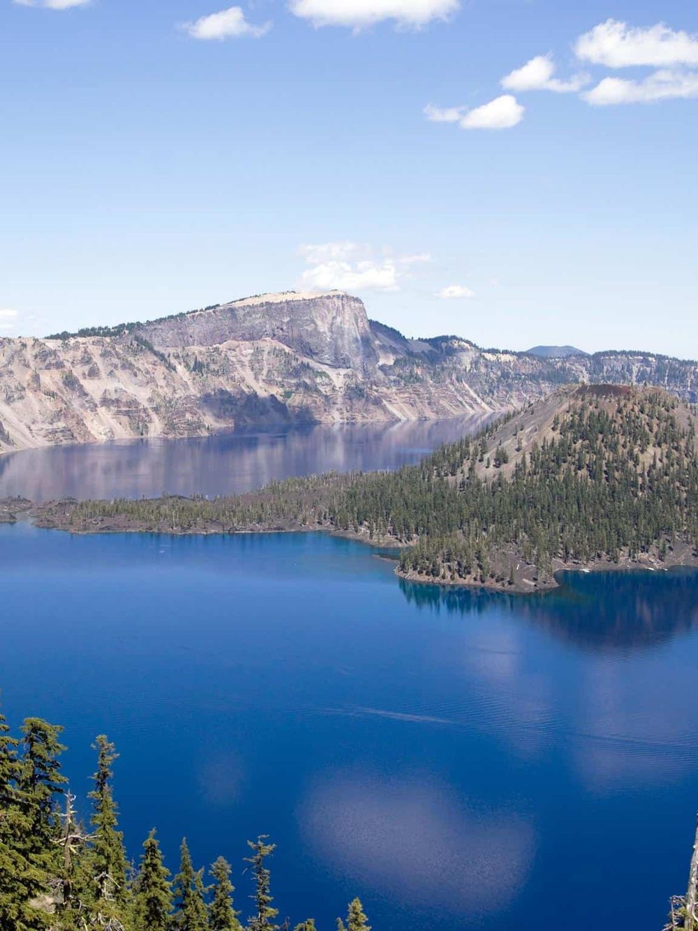 Serene lake surrounded by forested hills and mountainous landscape, perfect for outdoor adventures.