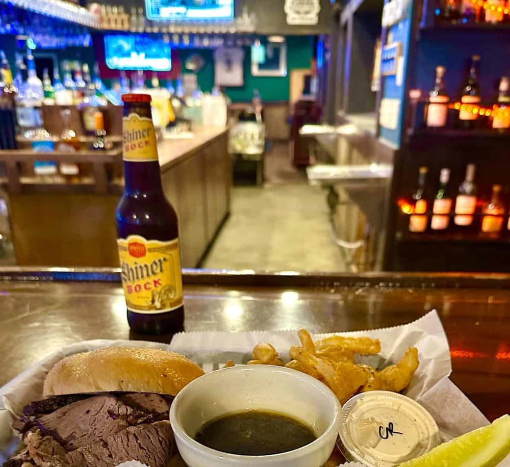 Cold beer and classic bar food at a lively sports bar with neon signs and a vibrant atmosphere.