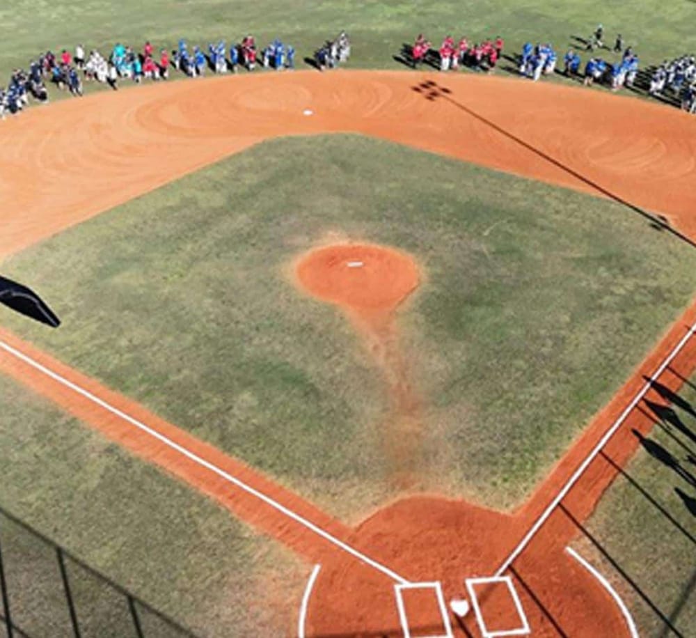 Aerial view of a baseball field with players and spectators, highlighting event planning and directions for community sports.