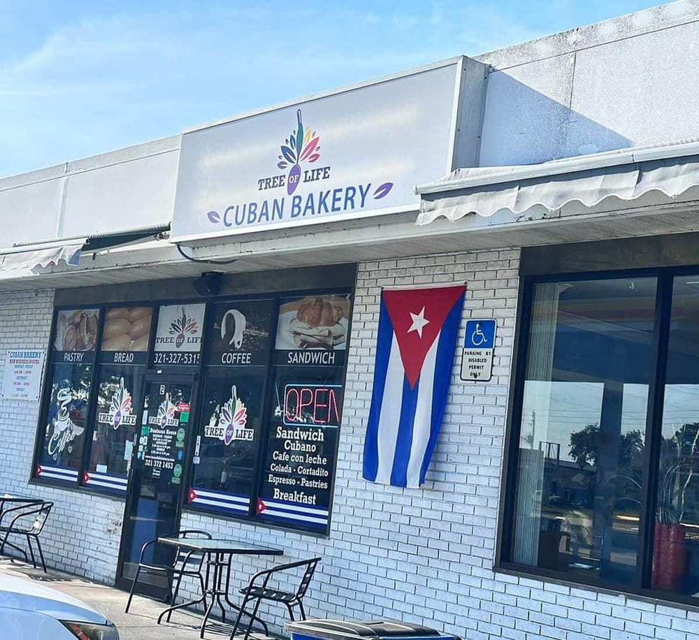 Colorful Cuban bakery storefront with Cuban flag, offering pastries, bread, coffee, and sandwiches.