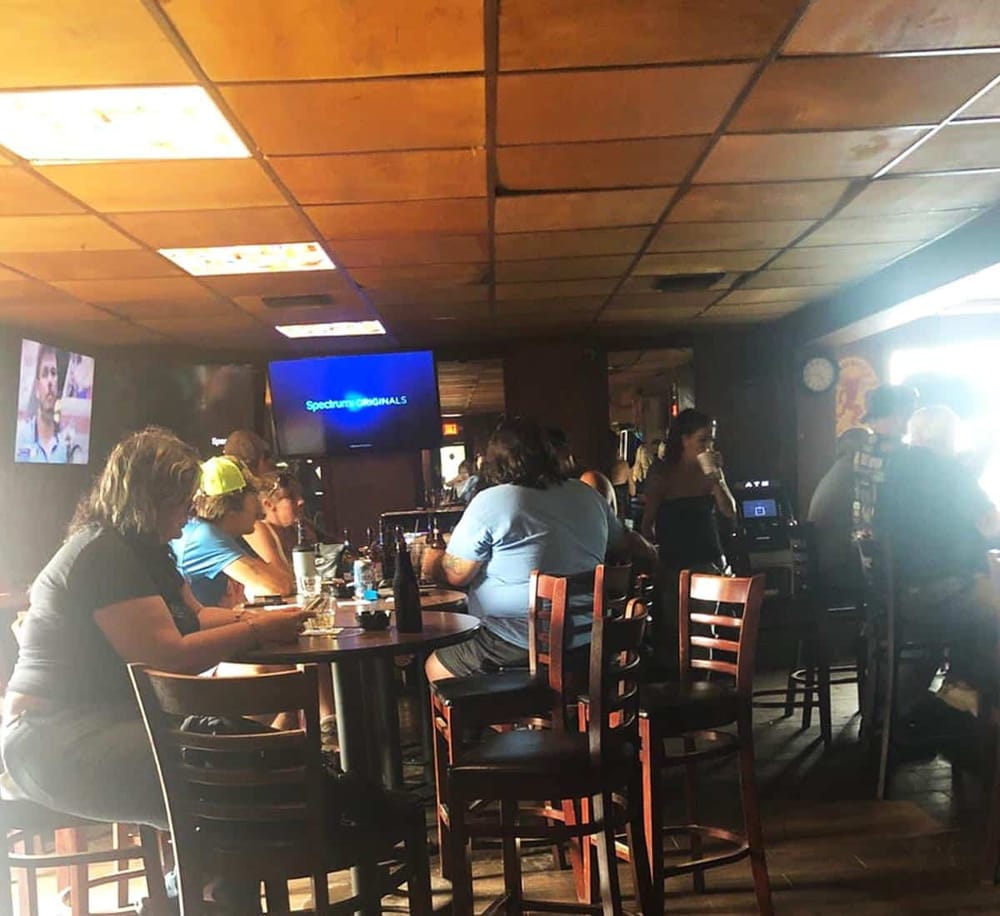 Comfortable bar with patrons watching sports on large screens, lively atmosphere at QuestForDirections.