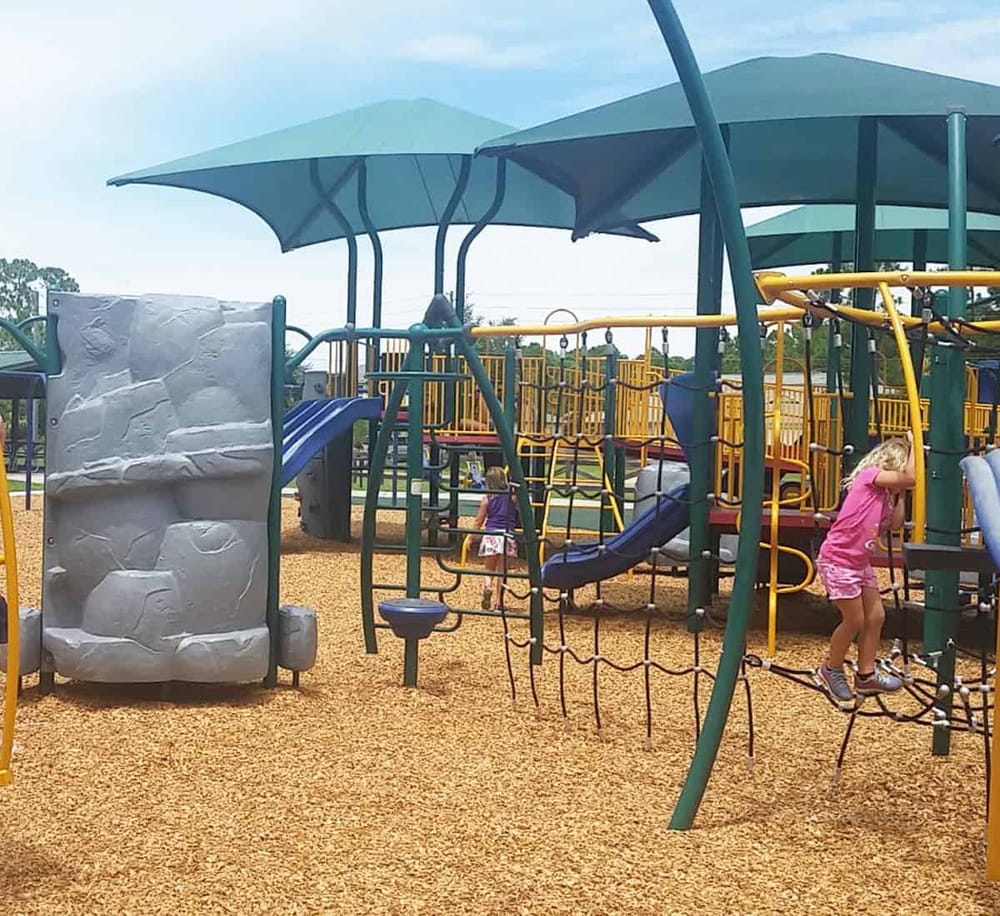 Colorful playground equipment with slides and climbing structures in an outdoor park setting.