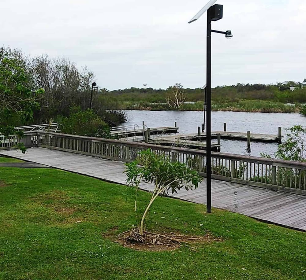 Solar-powered landscape lighting along a wooden pier at a scenic waterway.