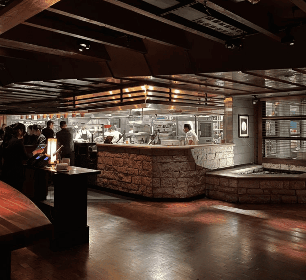 Cozy modern restaurant interior with open kitchen and warm lighting for a memorable dining experience.