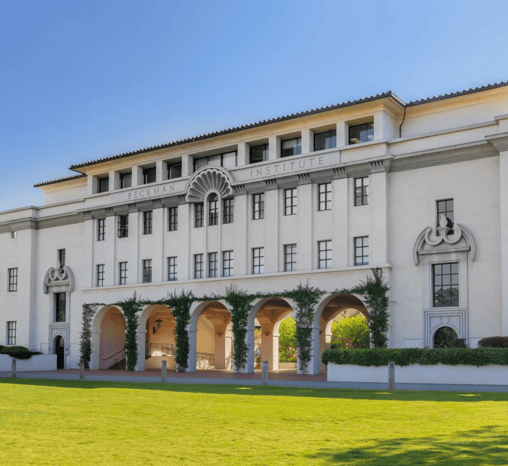 Elegant university building at Beckman Institute, featuring classical architecture and lush greenery.