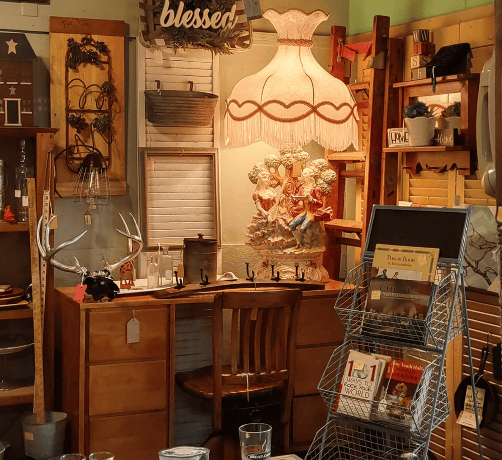 Antique rustic decor with a vintage lamp, wooden shelves, and decorative items in a cozy shop setting.