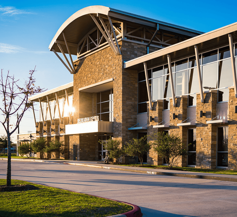 Modern healthcare facility with reception center in clear view, surrounded by greenery and open sky.