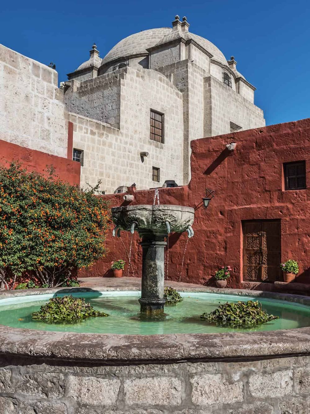 Ancient stone church with distinctive architecture and vibrant courtyard in Mexico City.