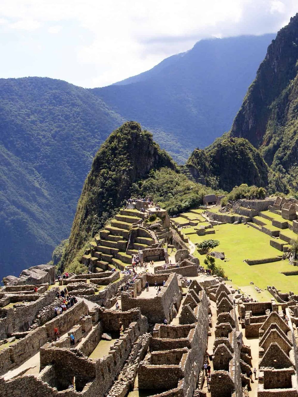Ancient Machu Picchu ruins surrounded by lush green mountains and vibrant blue sky, a top travel destination in Peru.