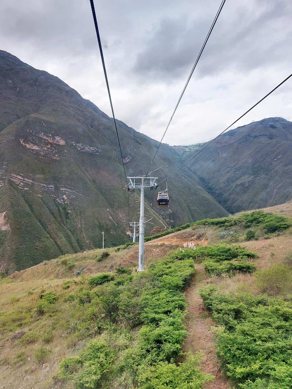 Panoramic view of a mountain landscape with a cable car system and lush green vegetation, perfect for adventure and travel enthusiasts.