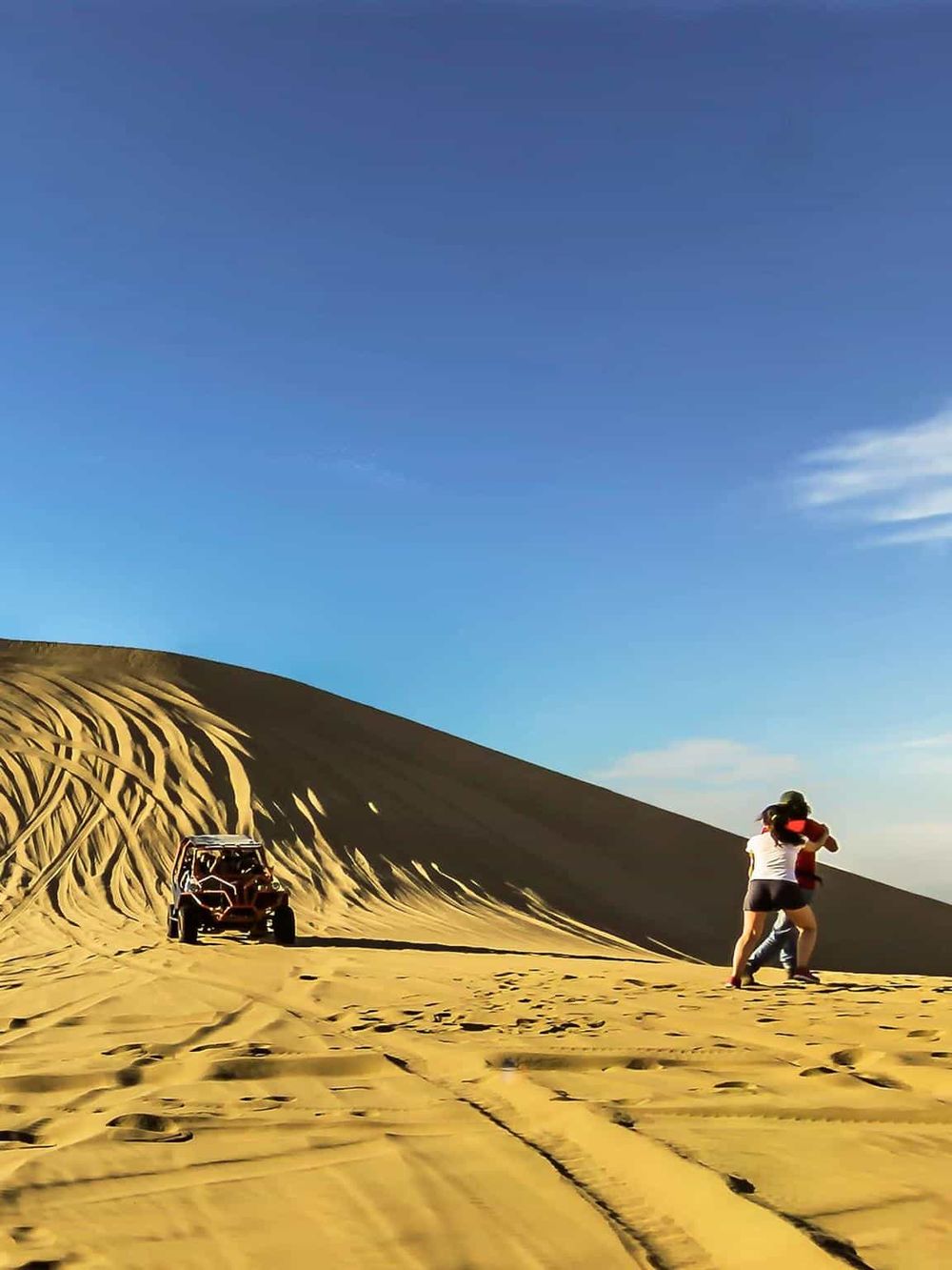 Sand dune exploration with ATV and visitors in desert landscape, adventure, and outdoor activity.