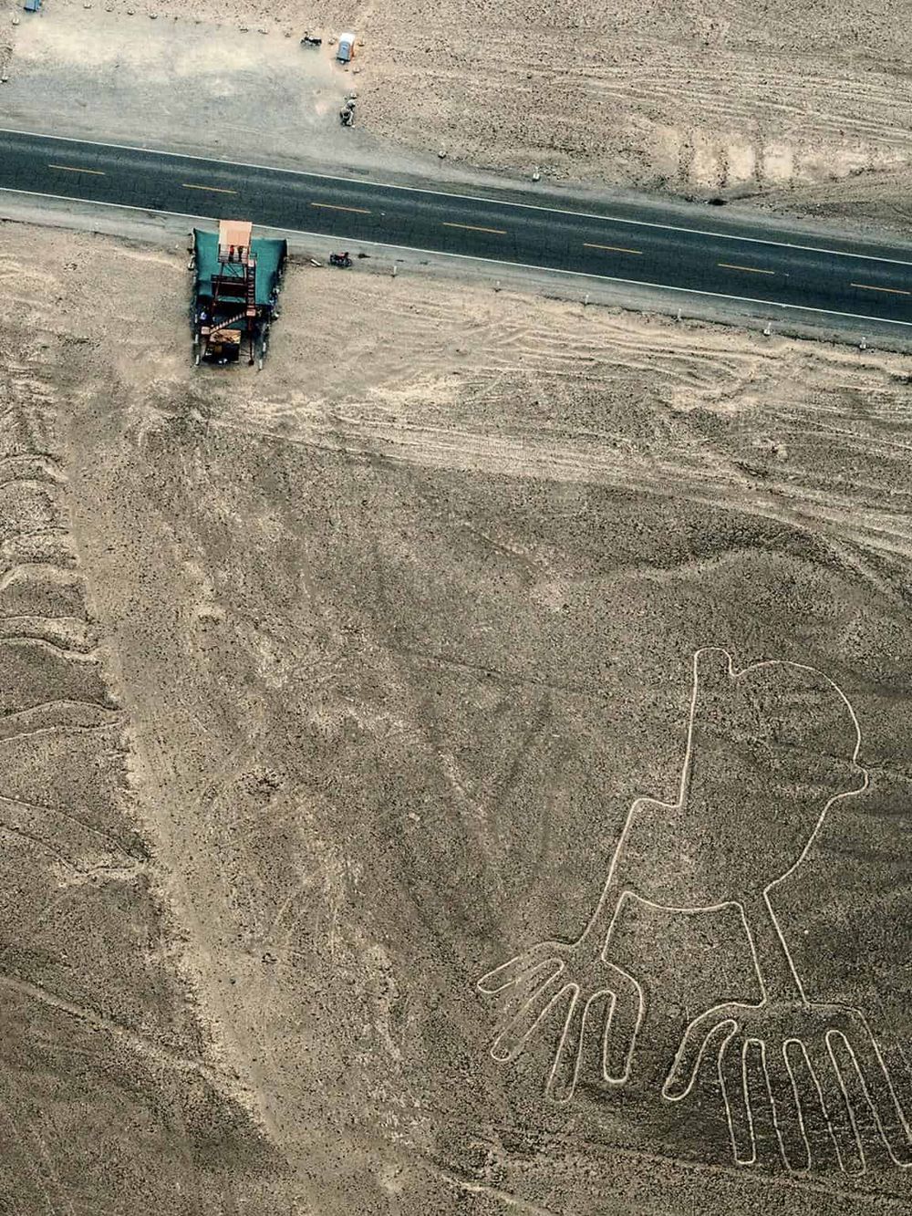Large elephant figure drawn in the dirt with construction equipment in a desert landscape, creative land art for road construction project.