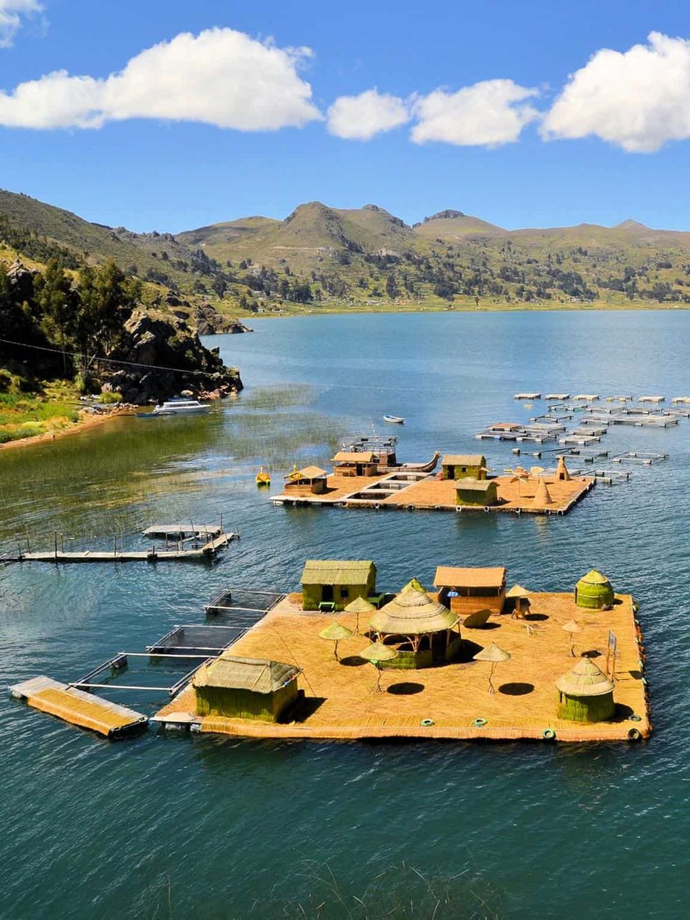 Floating resort with traditional huts on a serene lake surrounded by mountains in Africa.