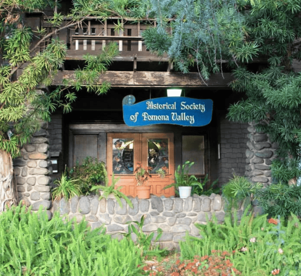 Historical Society of Pomona Valley building entrance with lush greenery and stone accents, showcasing local heritage.