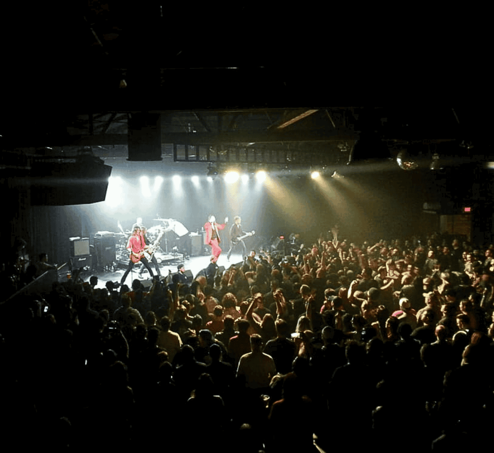 Bright concert stage with band performing and energetic crowd at QuestForDirections event.