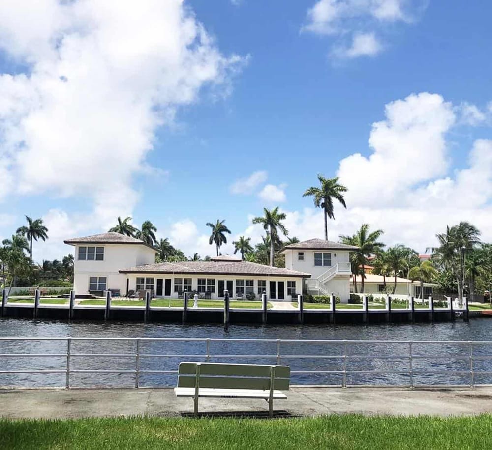 Waterfront luxury house with palm trees and clear blue sky in Florida.