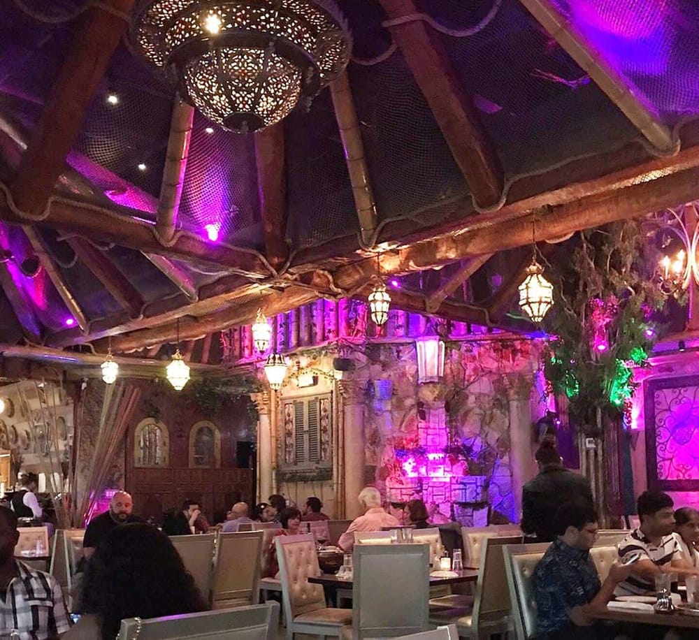 Vibrant indoor restaurant with colorful lighting, rustic decor, and diverse diners enjoying their meals.