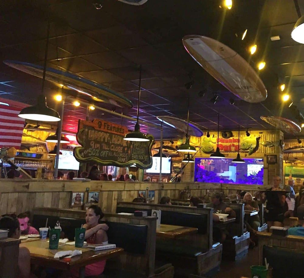Colorful surfboard decor, lively restaurant interior, casual dining atmosphere, and television screens at QuestForDirections.