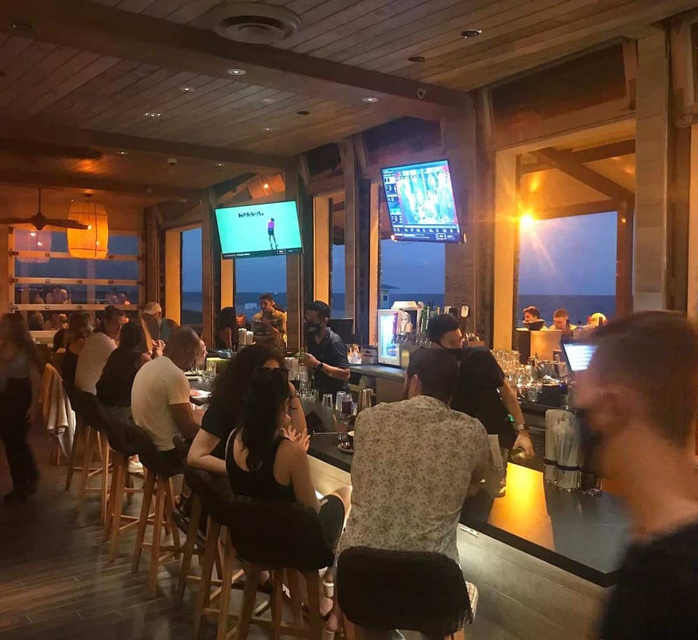 Bright beachside bar with ocean views and vibrant nightlife, perfect for socializing and watching sports events.