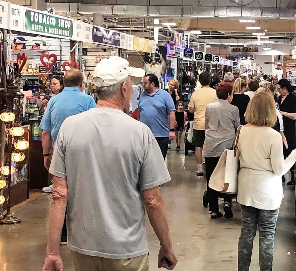 Busy indoor market with shoppers exploring various stalls and shops.