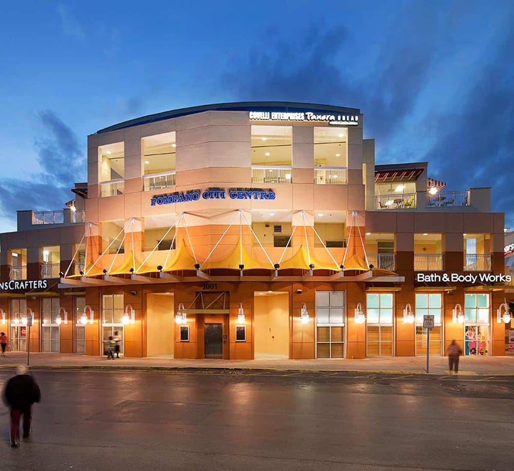 Modern shopping mall at dusk with illuminated storefronts and signage for Bath & Body Works and Crafters.