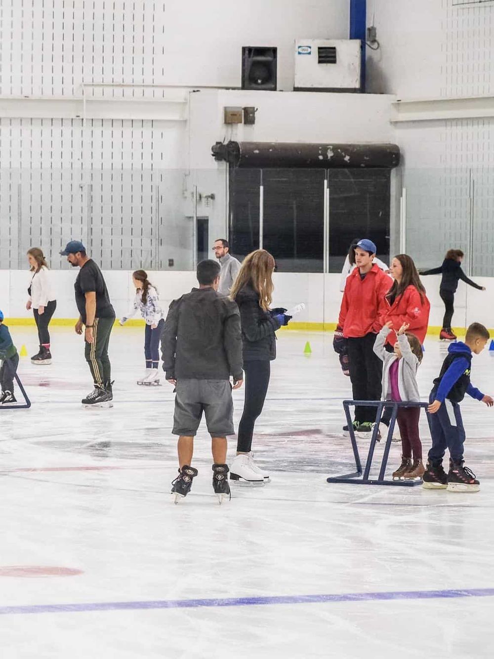 Children ice skating at indoor rink, learning experience, family fun, skate lessons, recreational activity, beginner skating.