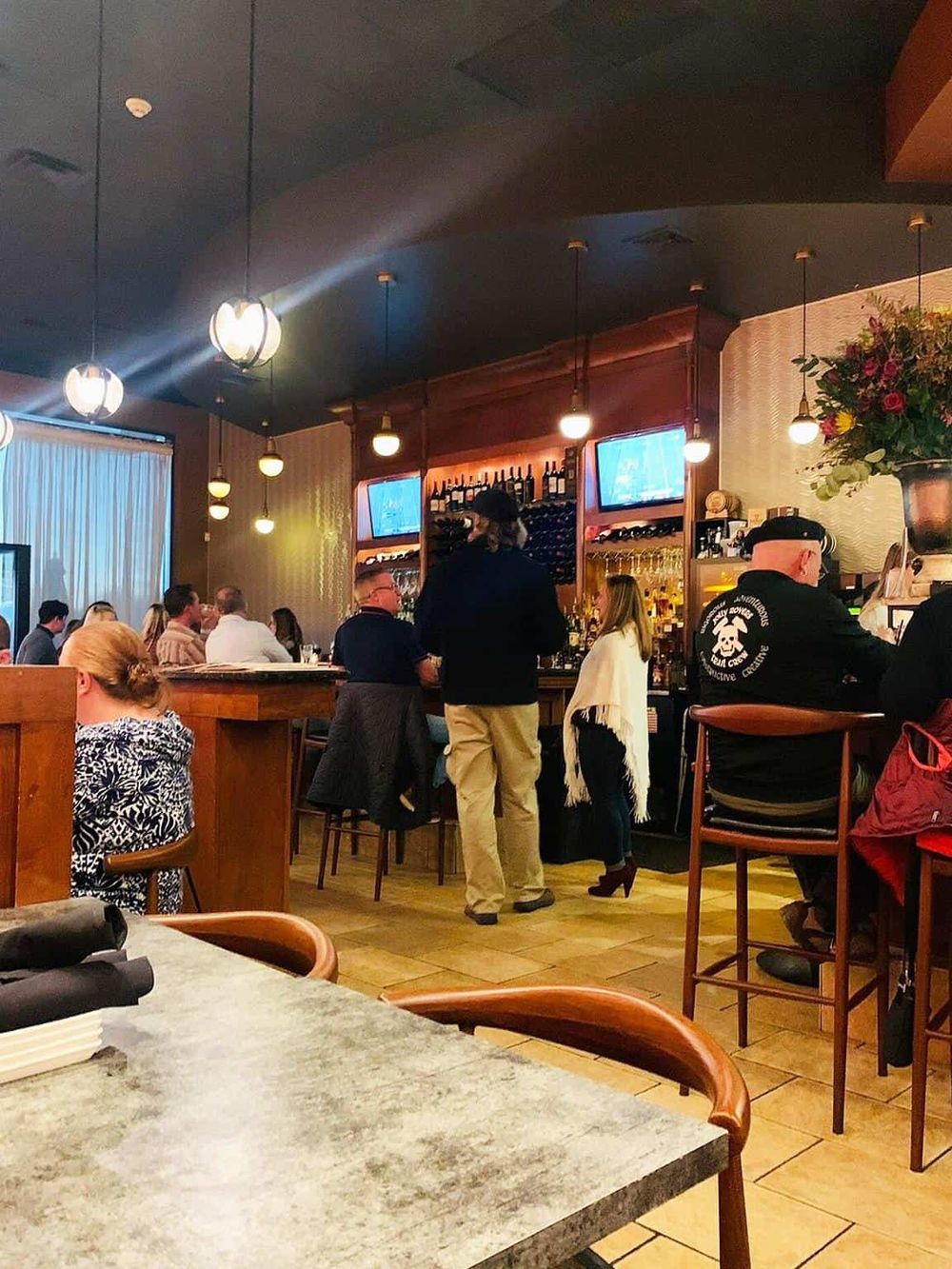 Cozy restaurant interior with bar, guests dining, and attentive staff, perfect for food and drink experiences.