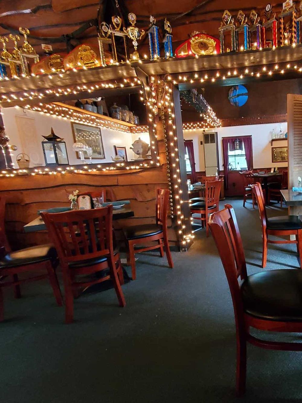 Cozy restaurant interior with wooden furniture, festive string lights, and a warm, inviting atmosphere.