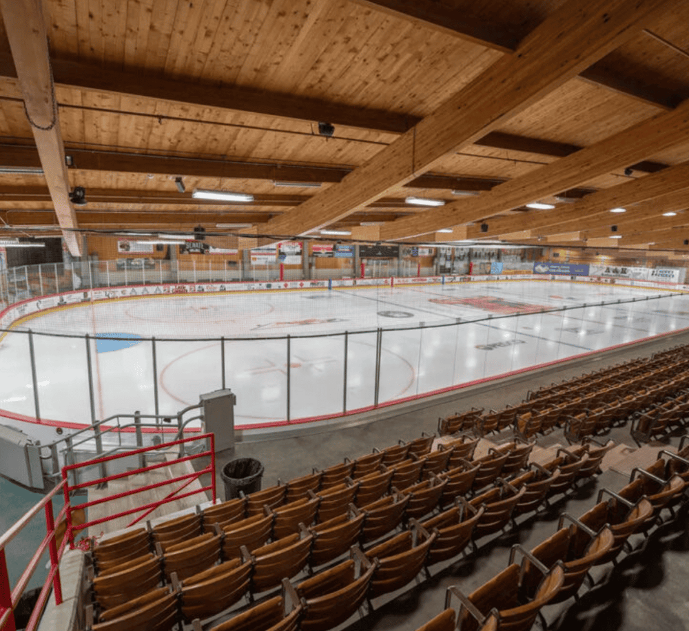 Ice hockey rink with wooden ceiling and seating area, ideal for sports events and tournaments.